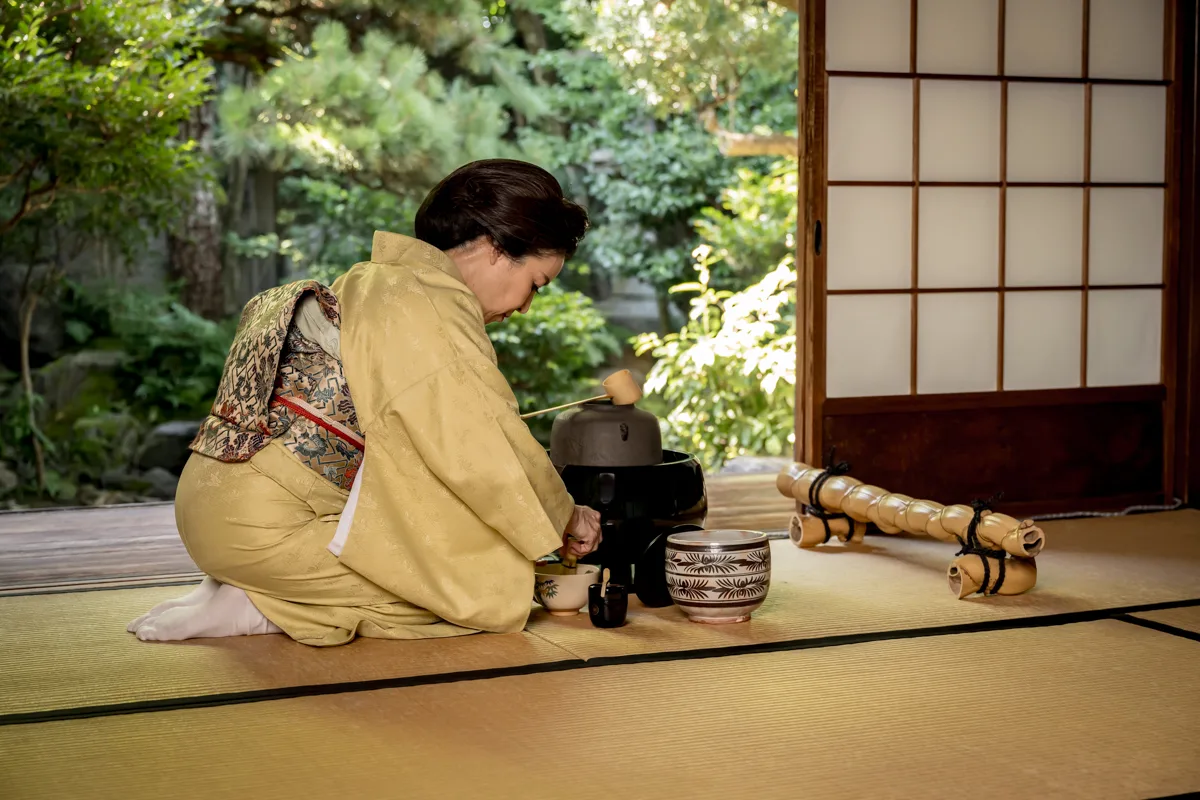 A tea host preparing matcha beside the garden